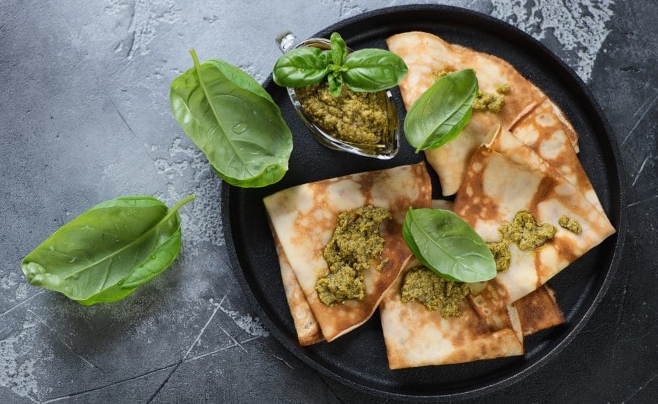 Crepes with basil pesto sauce on a metal plate, view from above,